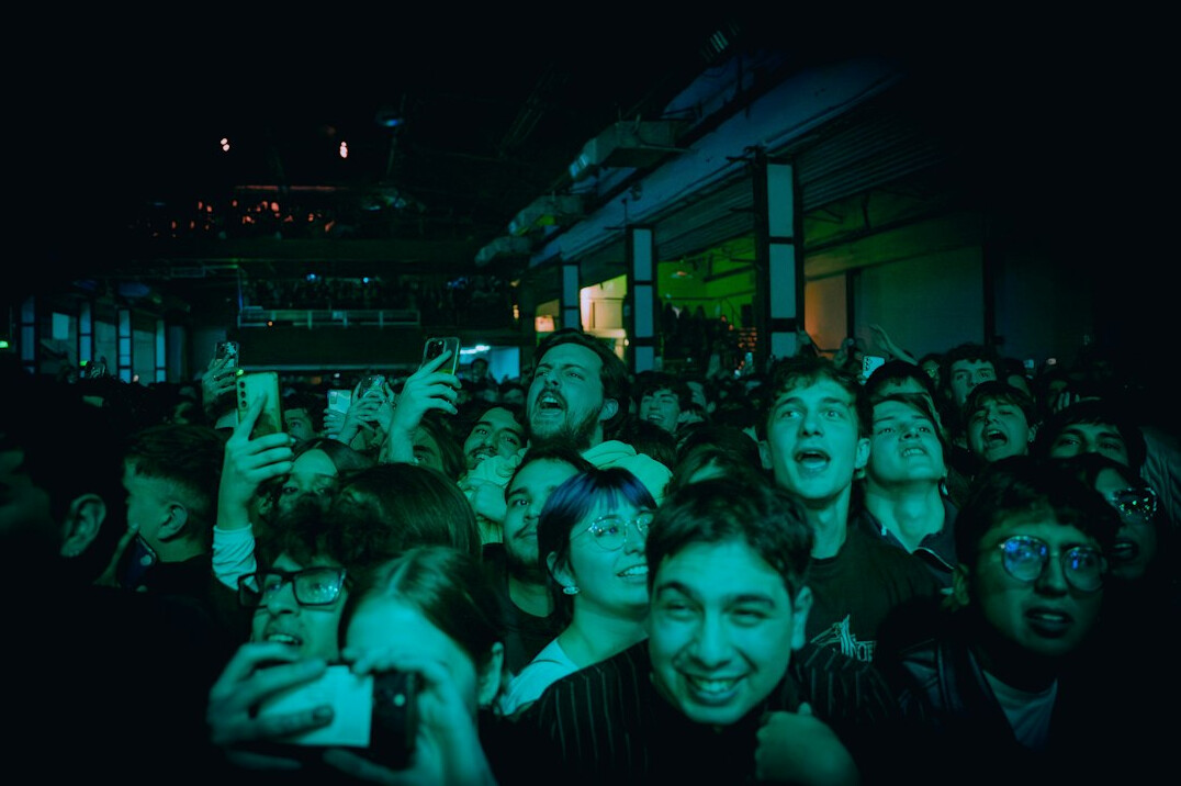 Crowd of young people queuing outside a concert venue at night